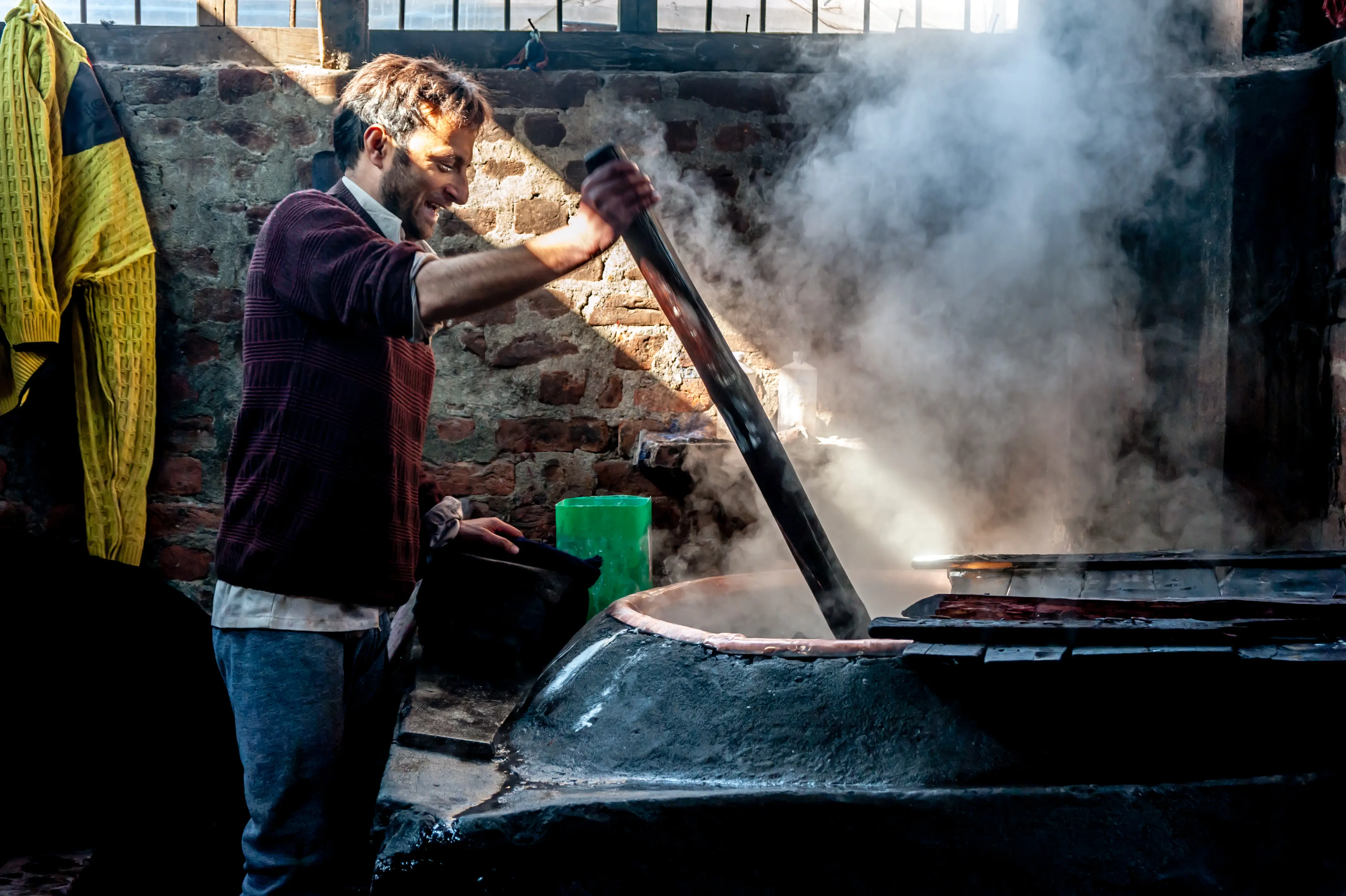 Yarn and fabric being dyed by hand over a wood fire